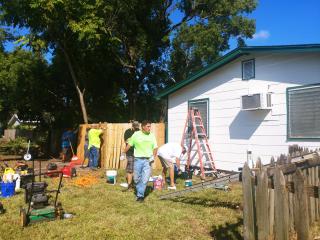 Volunteers repairing fence and house.