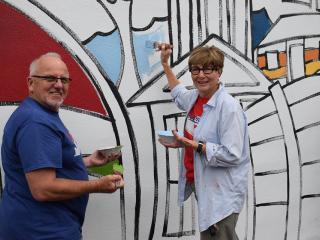 Two adults painting mural.