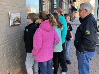 Group of children looking at plaque.
