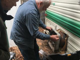 Volunteers removing water heater from trailer.