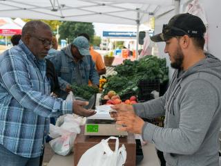 Adult purchasing vegetables at farmer's market.