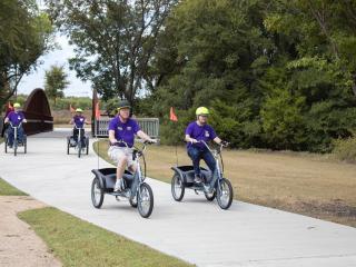 Group of older adults riding 3 wheeled bikes.
