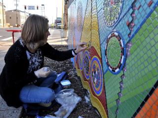 Artist installing mosaic tiles for mural.