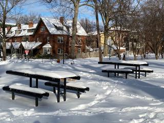 Picnic tables installed, covered with snow.