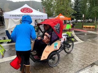 Two individuals in Trishaw with rain cover.