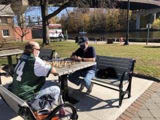 Two men playing on one of two outdoor chess tables.