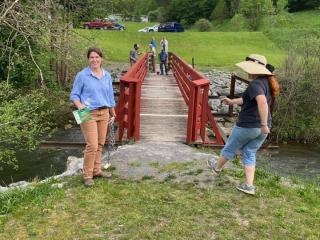 Two women standing by trail bridge.