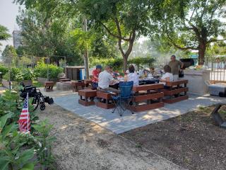 Gardeners gathering to share food and friendship at tables and benches.