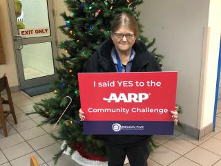 Woman with "I said yes to AARP Community Challenge" sign.