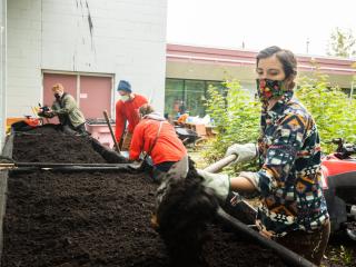 Volunteers filling raised beds with soil.