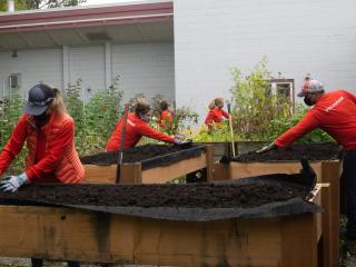Volunteers filling raised beds with soil.