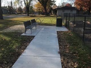 Two benches, trashcan, and new sidewalk to relocated garden.