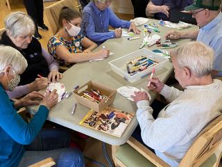 Older adults coloring feathers for wing art installation.