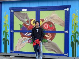 Artist Mario Dimas with his mural of food and culture.