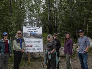 Group of hikers with "Scenic Overlook Platform Coming Soon" sign.