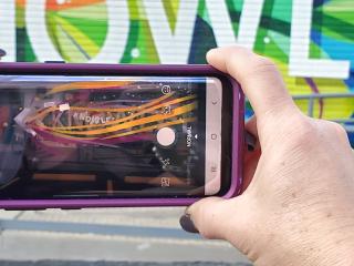 Viewing mural through smartphone app to see 3D image.