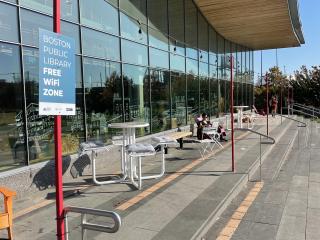 People using outdoor free wi-fi zone adjacent to library.