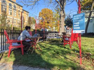 People using outdoor free wi-fi zone adjacent to library.