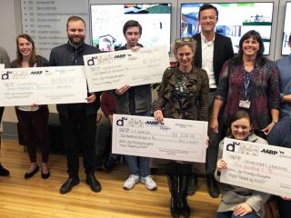 Design competition winners with large checks.