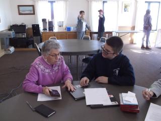 Student teaching older adult to use tablet.