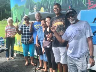 Group of older adults in front of community mural.