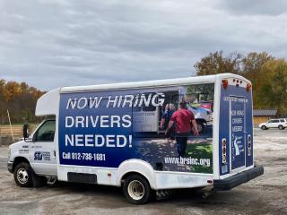 Transportation shuttle with "now hiring" decal.