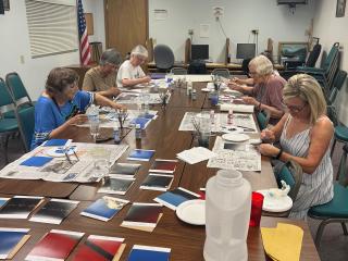 Older adults painting pieces of art panels.
