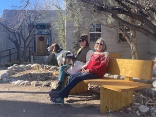 Two people and a dog sitting on a bench.