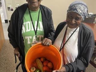 Two older adults showing garden harvest.