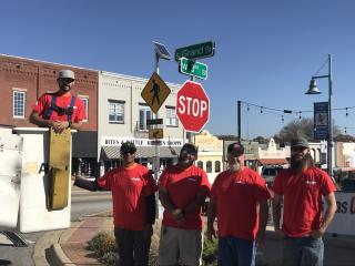 Crew standing in front new flashing pedestrian beacon sign.