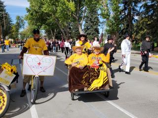 Two older adults riding in trishaw in homecoming parade
