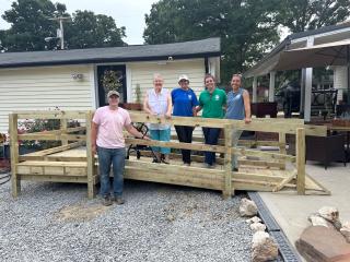 Homeowner standing on new ramp with volunteers.