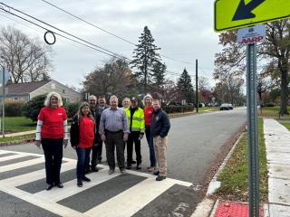 Group standing in new crosswalk, new sidewalk, and new signage.