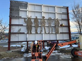 Installing metal cutouts of mural.