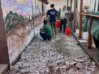 Renovating pavers in front of mural.