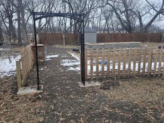 New iron arbor and wood fencing at entrance to garden.