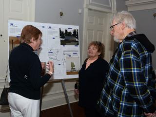 Event attendees look at poster of accessory dwelling unit design.