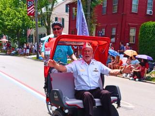 Veteran riding in trishaw during 4th of July parade.