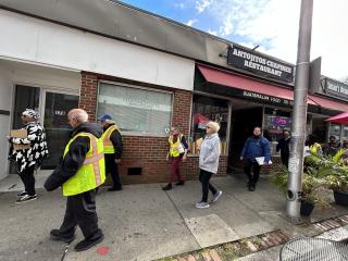 Participants walking along sidewalk in front of businesses.