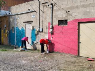 Community members painting mural in an alley.