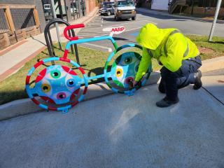 Installing a painted bicycle-shaped bike rack.