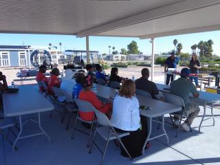 Attendees learning about gardening under a shade awning.