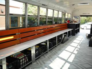 Interior of book bus with reading bench and materials under bench.