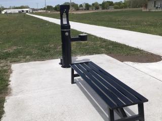 New bench and drinking fountain along walking path.
