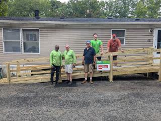 Volunteers standing in front of completed entrance ramp to a house.