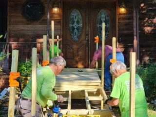 Volunteers building entrance ramp to a house.