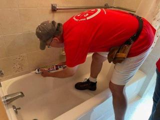 Volunteer caulking bathroom tub.