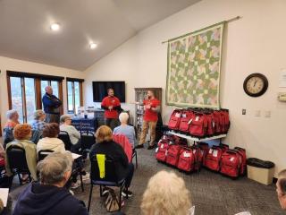 Emergency preparedness training with red rolling backpacks for distribution.