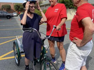 Helping woman on tricycle fit helmet.