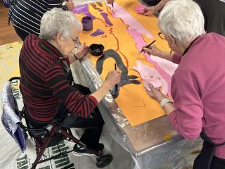 Older adults painting mural panels.